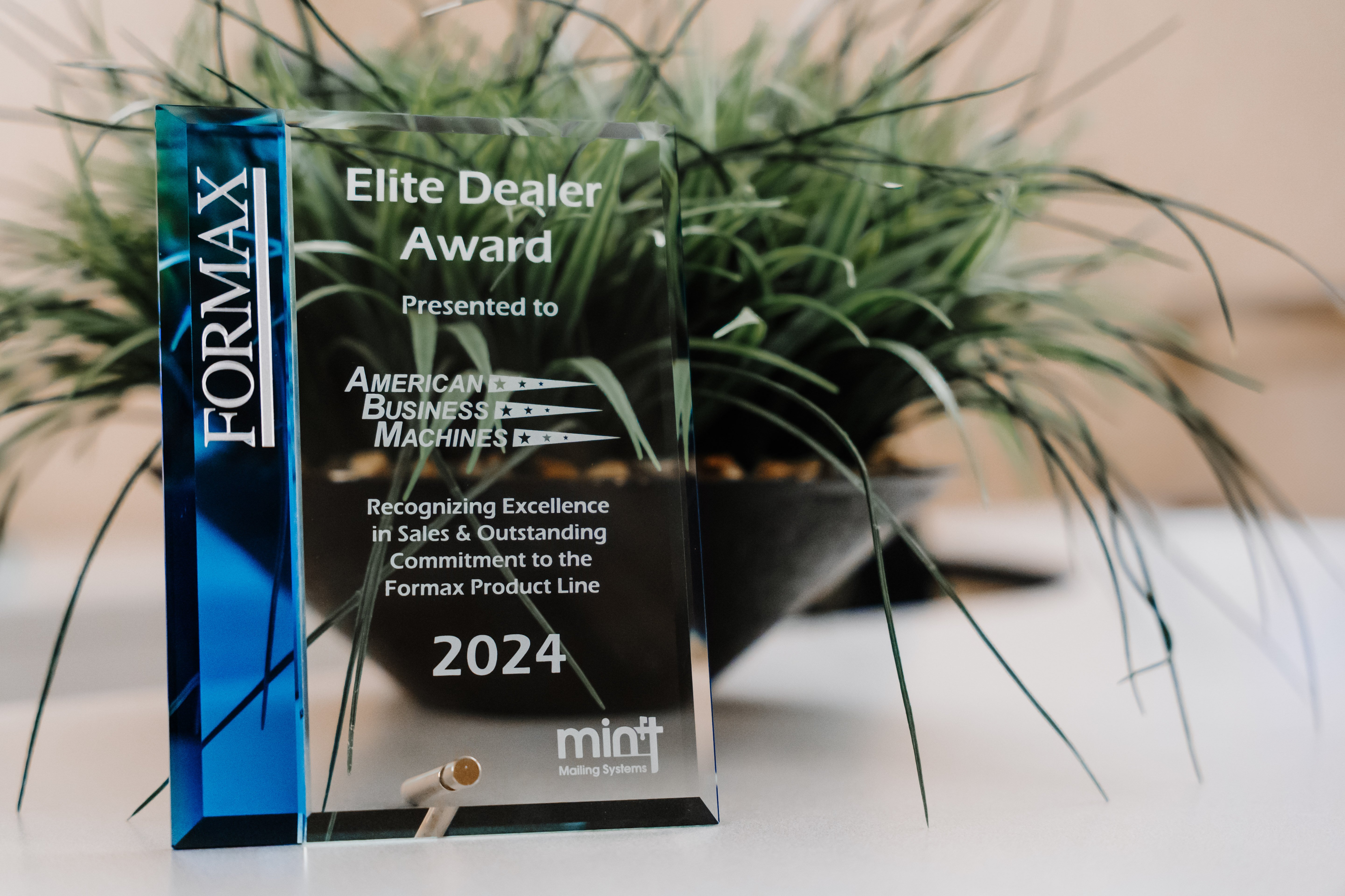 Crystal clear and blue plaque that reads Formax Elite Dealer Award presented to American Business Machines 2024